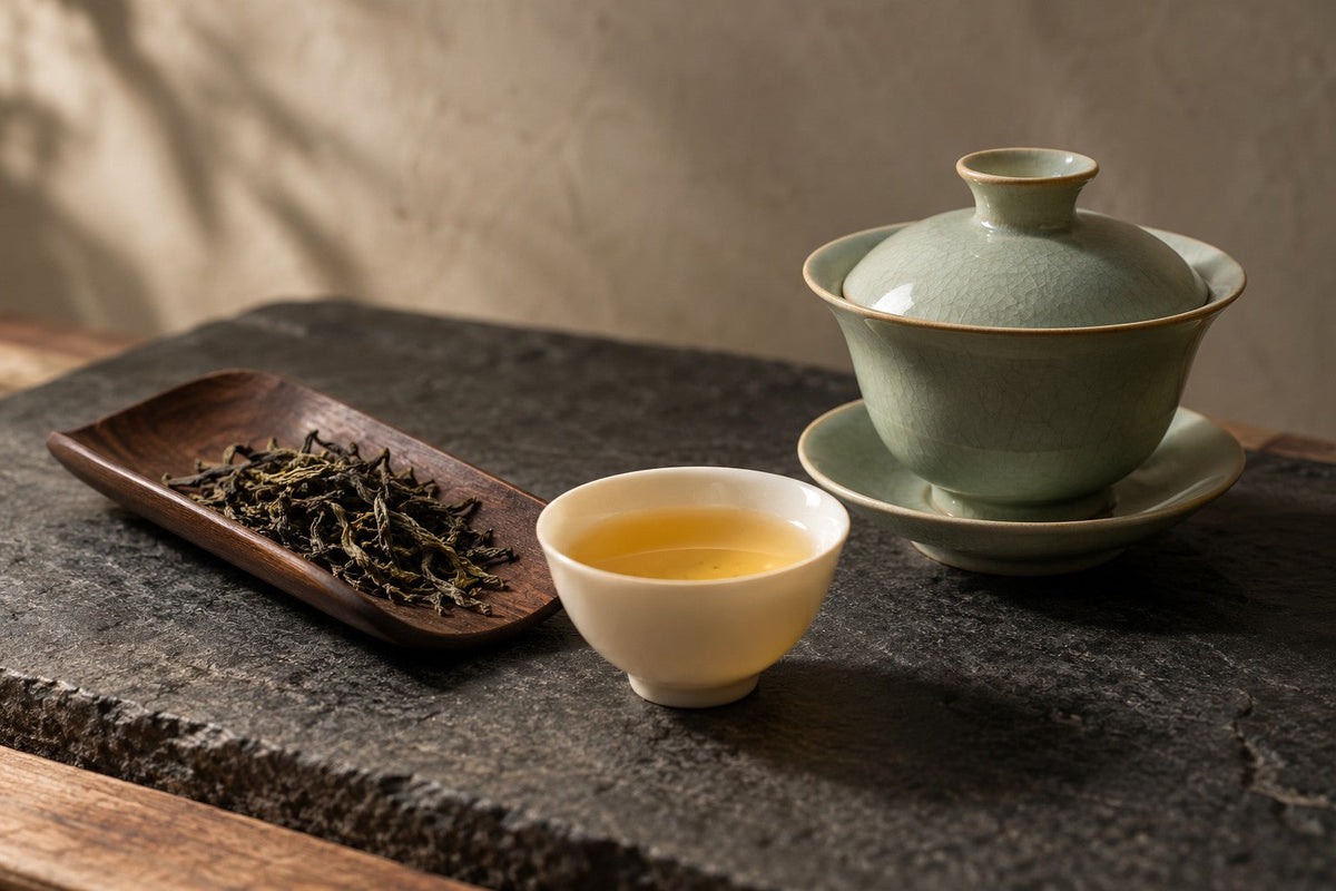 Sage green gaiwan and golden tea on charcoal stone