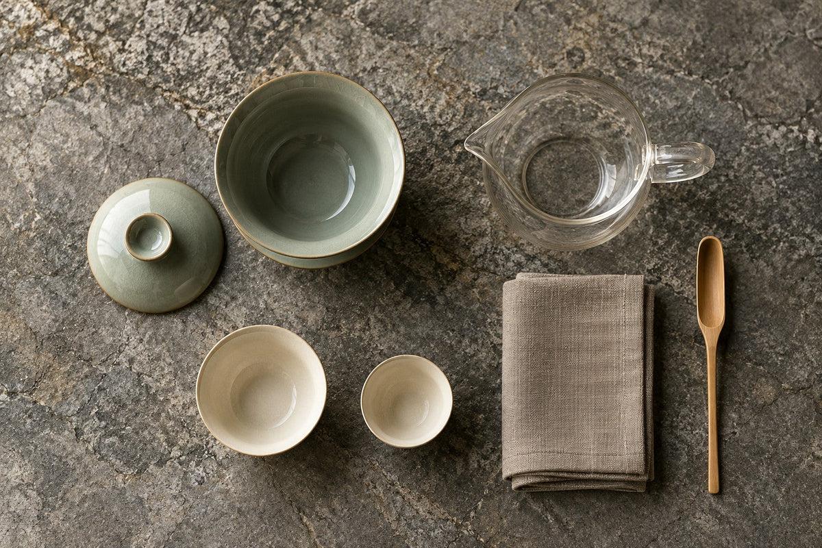 Overhead arrangement of a gaiwan, pitcher, cups, cloth and tea scoop