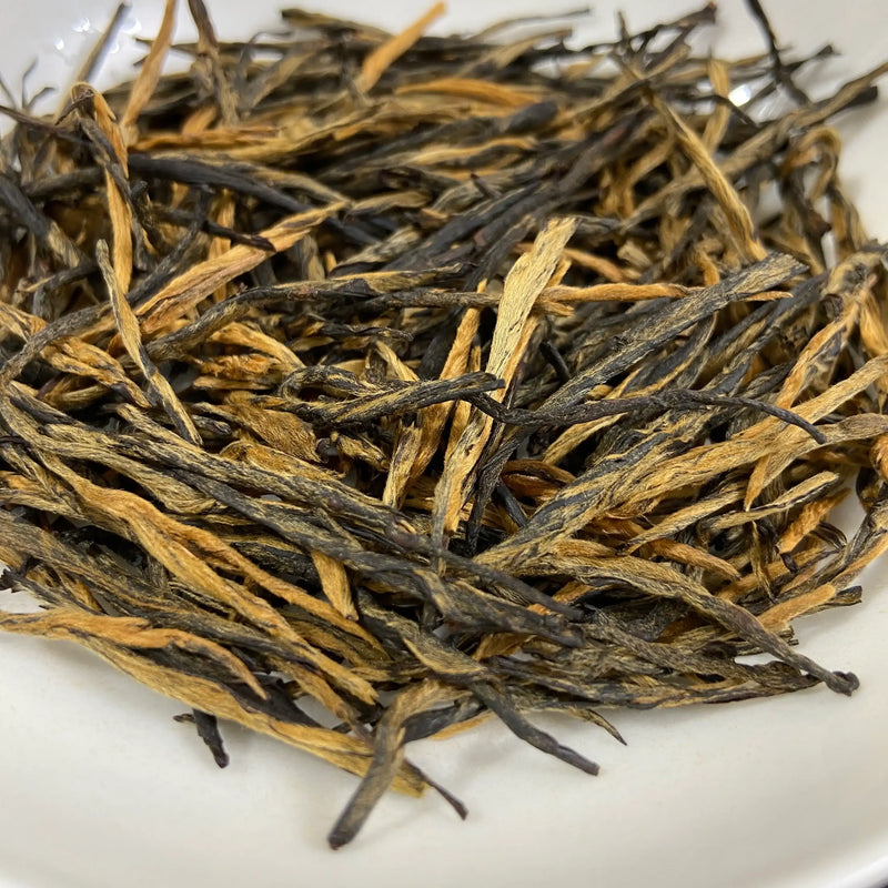 Close-up of dried tea Dian Hong Song Zhen «Pine Needles» — 2026 leaves on a white background