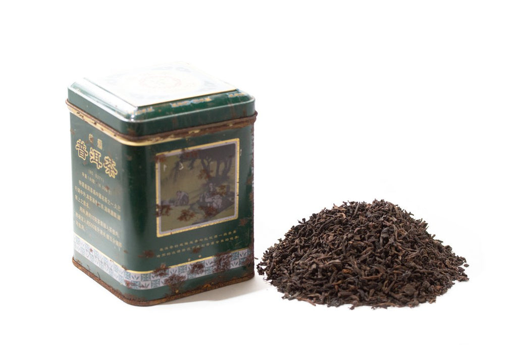 Macao Chen Nian Pu-erh tea tin beside loose tea leaves