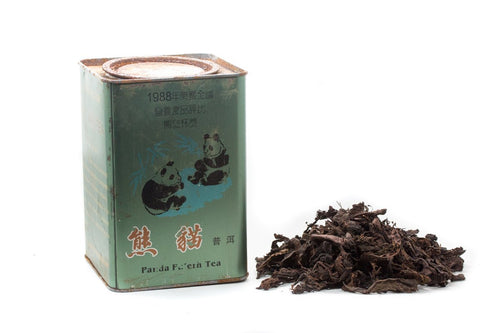 Big Panda ripe Pu-erh tea tin beside loose leaves